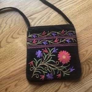 Crossbody purse with flower design on brown suede.